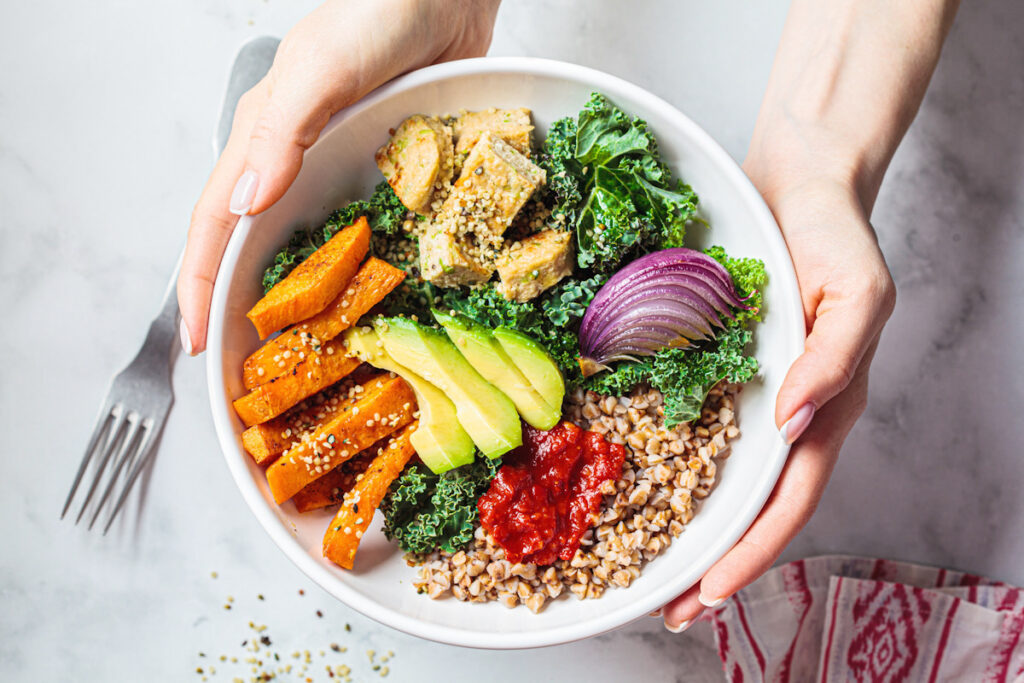 Photo shows a vegan vegetable bowl including protein-rich tofu, greens, and grain.