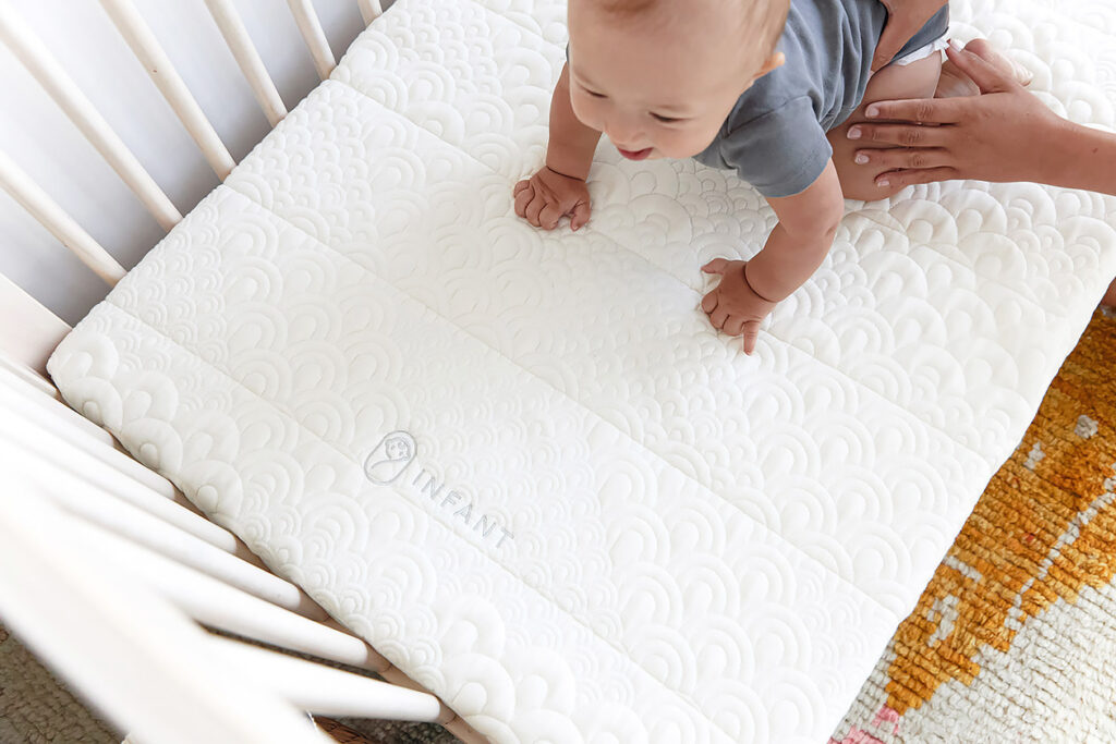 Photo shows a baby playing on the Brentwood Home crib mattress.