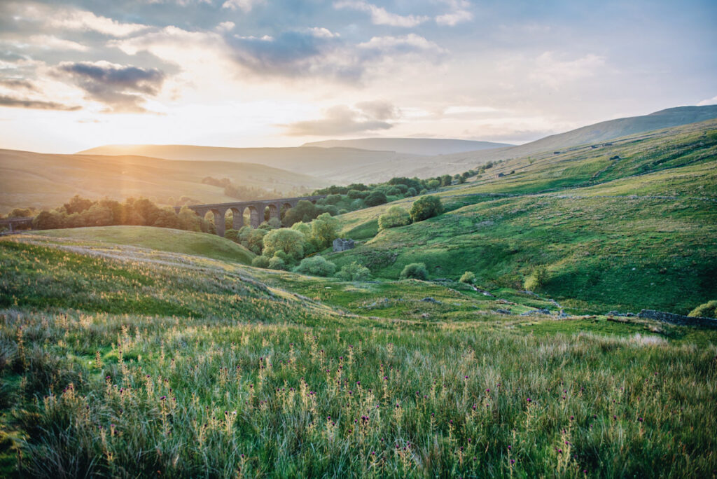 Photo features rolling green hills and an aquaduct of the kind common in England and the UK.