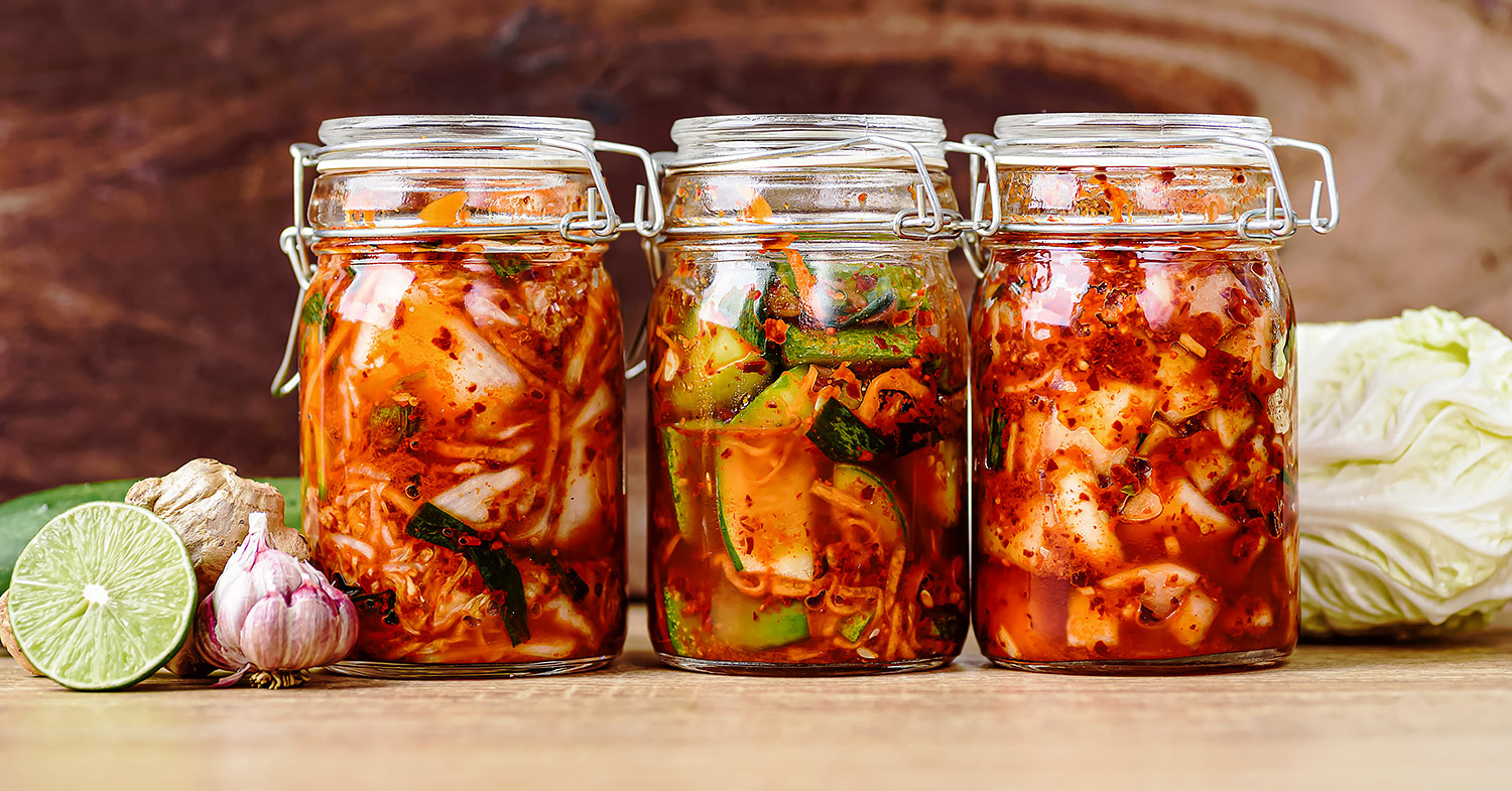 Close-up image of three full mason jars filled with fermented vegetables.