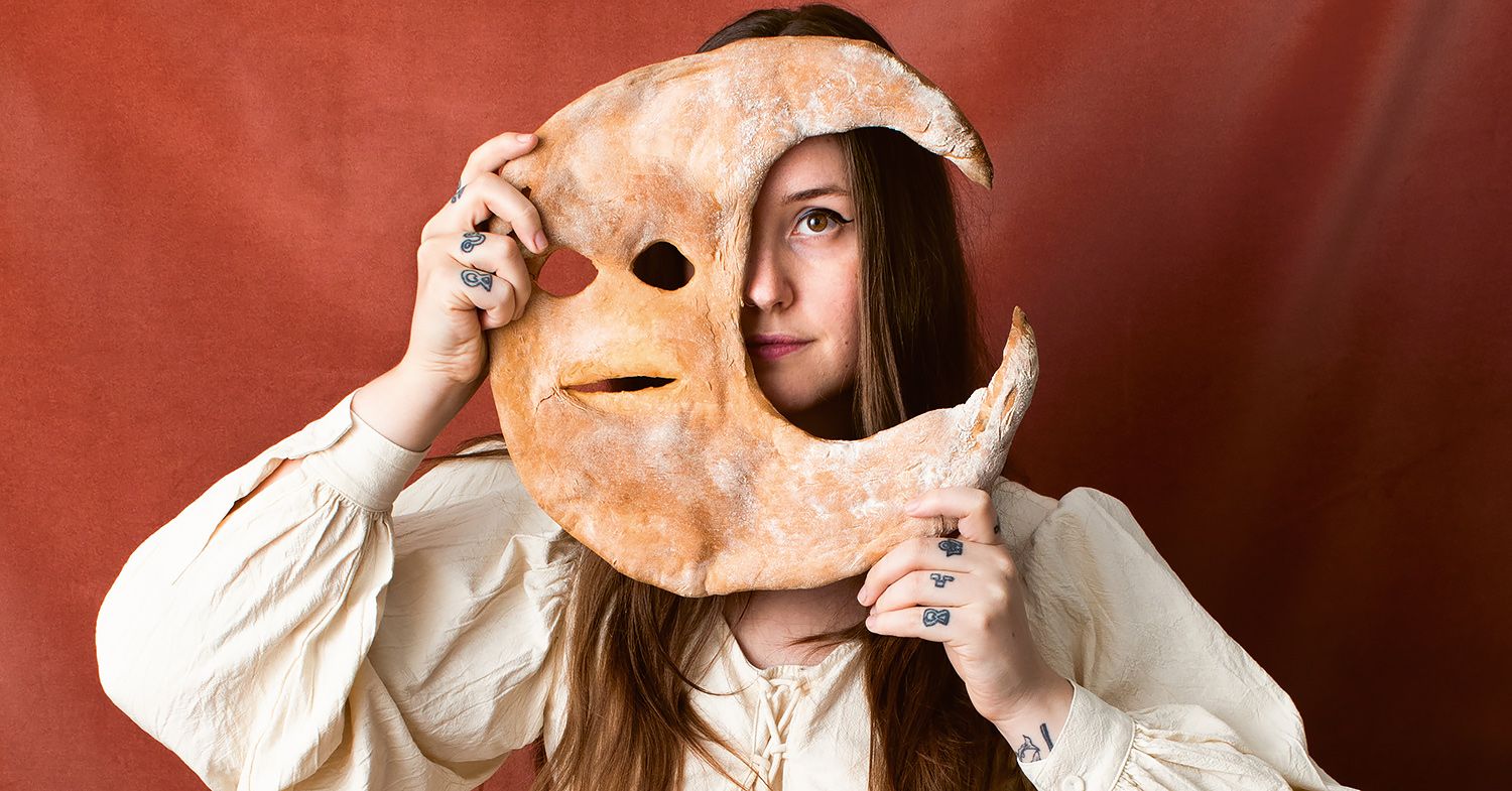 A woman holds up a moon-shaped pastry in front of her face.
