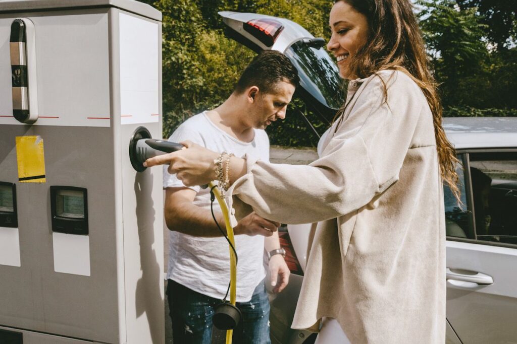 A woman and a man stand next to an electric charging station