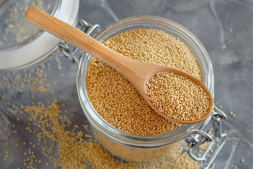Photo shows loose amaranth in a container with a wooden spoon. Here's how to cook with amaranth.