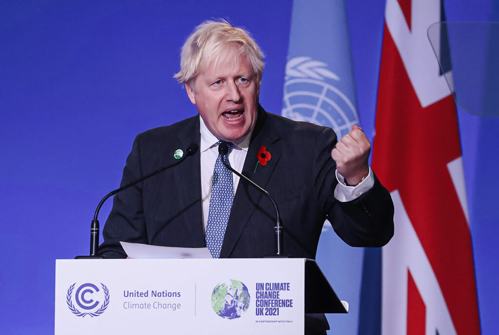 Photo shows British Prime Minister Boris Johnson speaking at COP26. The UK's carbon-storing moorland us burning.