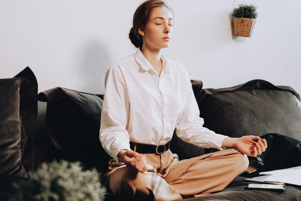 Photo shows someone meditating cross-legged at home. Meditation app subscriptions make a great self-care themed gift.