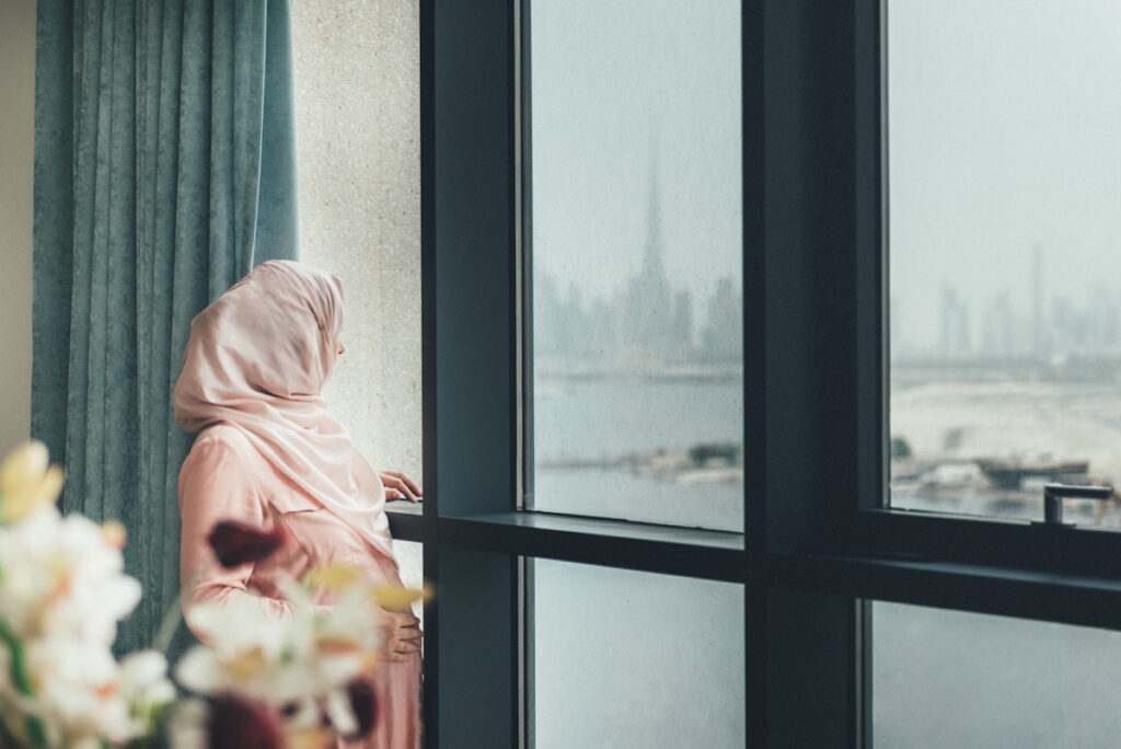 Photo shows a pregnant Muslim woman standing next to a window in the UAE.
