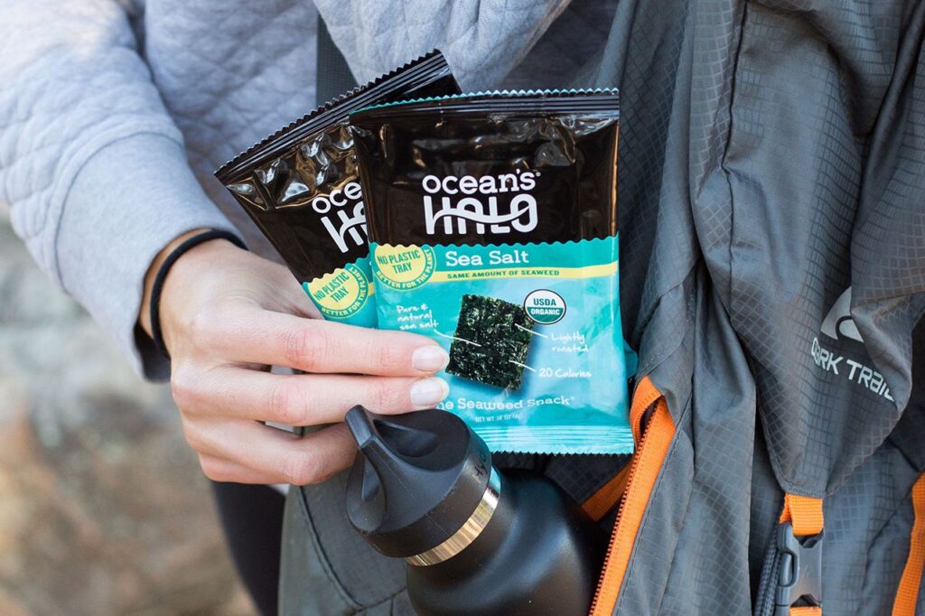 Photo shows a person holding two packages of Ocean's Halo sea salt-flavored seaweed snacks