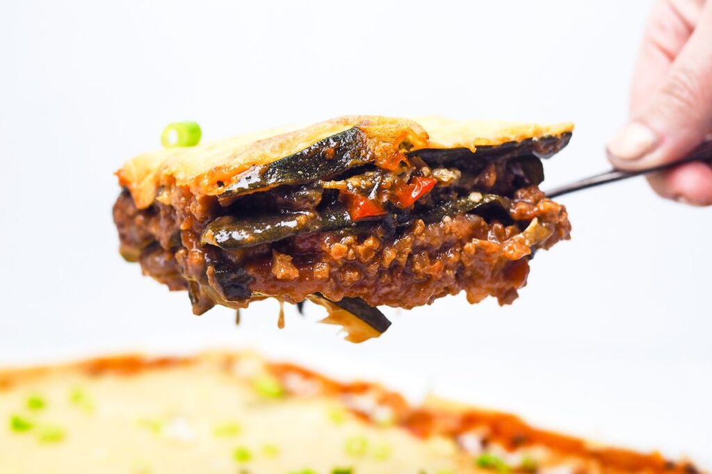 Photo shows a slice of zucchini lasagna with plant-based meat sauce on a fork