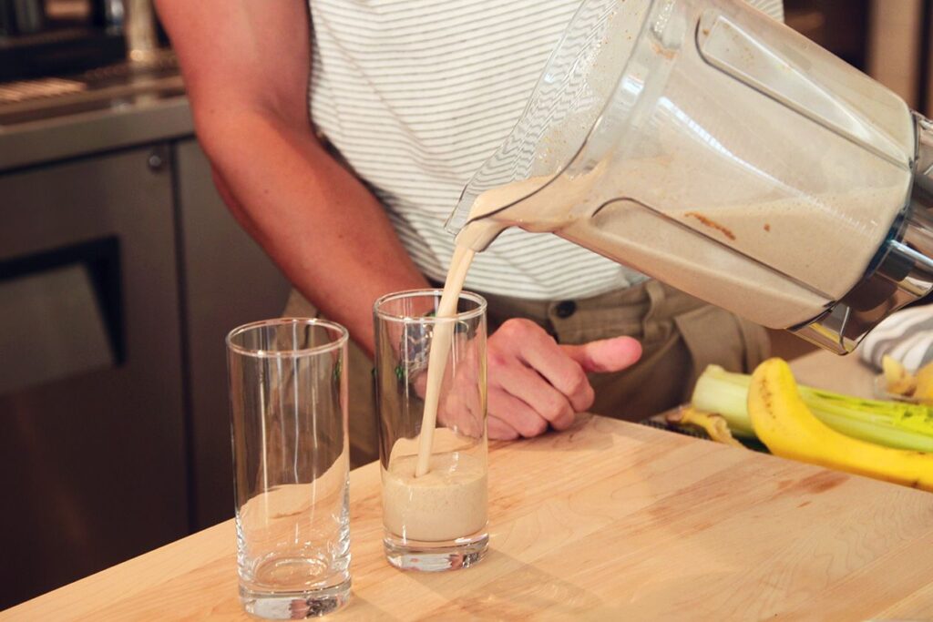 Photo shows Antoni Porowski pouring a vegan protein shake into a glass