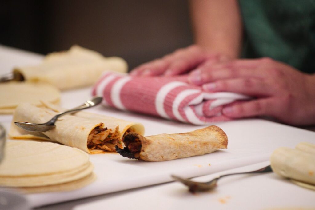 Photo shows a cutting board with refried bean taquitos on it