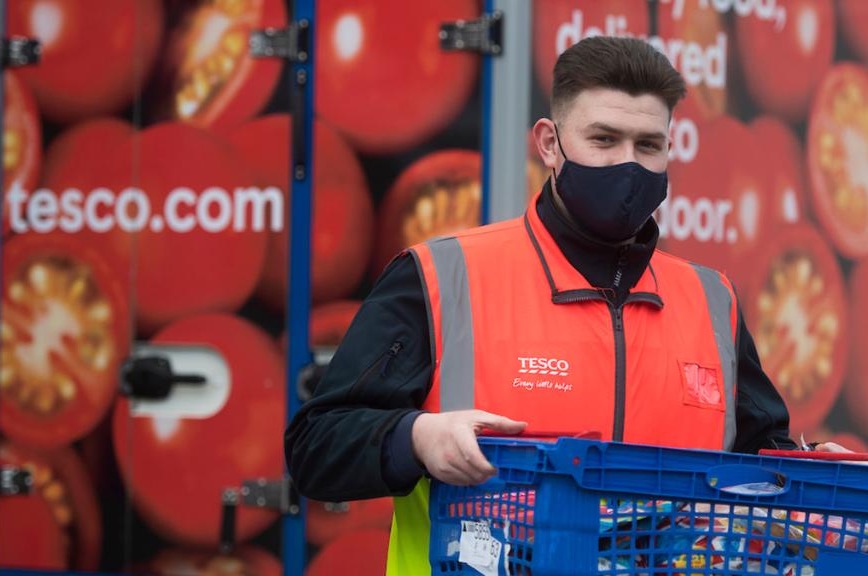 Photo shows a delivery worker for Tesco's dropping off food. Tesco is the UK's largest supermarket and its delivery truck fleet will be going electric.