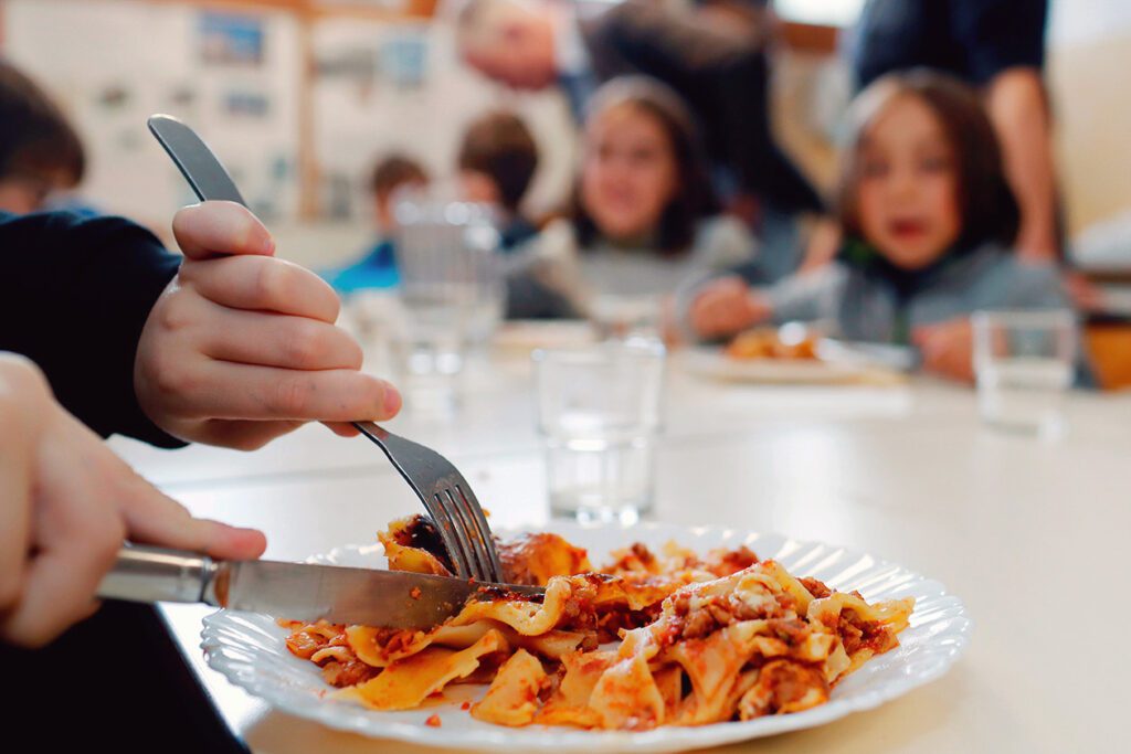 Photo shows a close up of a child's plate with other young people in the background. Our Lady of Sion just became the first UK school to launch an entirely vegan kitchen producing meatless lunches.